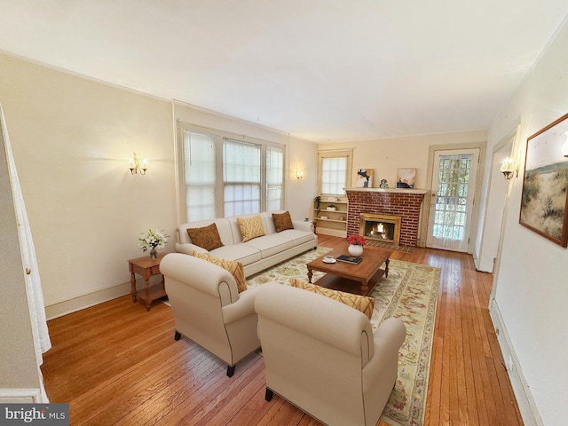 living room with a healthy amount of sunlight, light hardwood / wood-style floors, and a brick fireplace