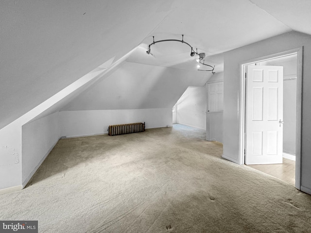 bonus room with lofted ceiling, radiator heating unit, and light carpet