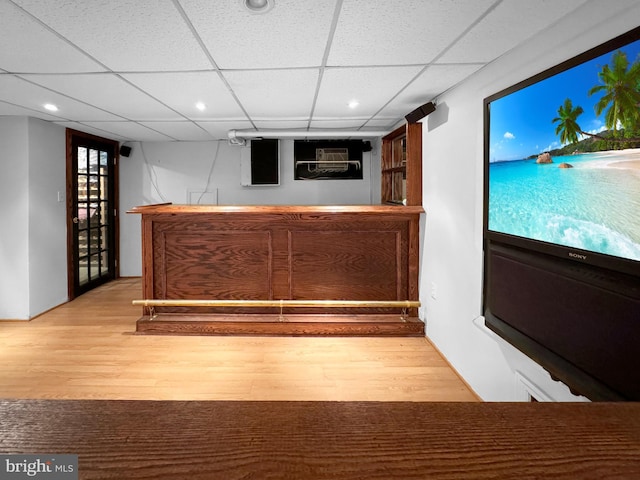 bar with a paneled ceiling and light hardwood / wood-style floors