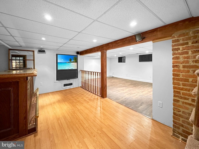 basement with a paneled ceiling and hardwood / wood-style floors