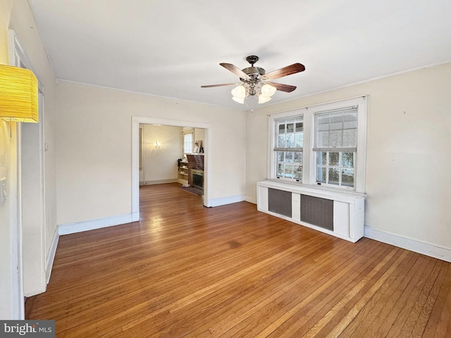 empty room featuring radiator heating unit, wood-type flooring, and ceiling fan