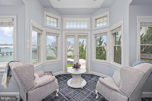 sunroom featuring a water view and lofted ceiling