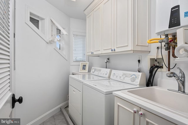 laundry area featuring sink, light tile patterned floors, washer and clothes dryer, and cabinets