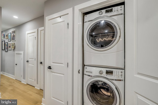 clothes washing area featuring stacked washer and dryer and light wood-type flooring