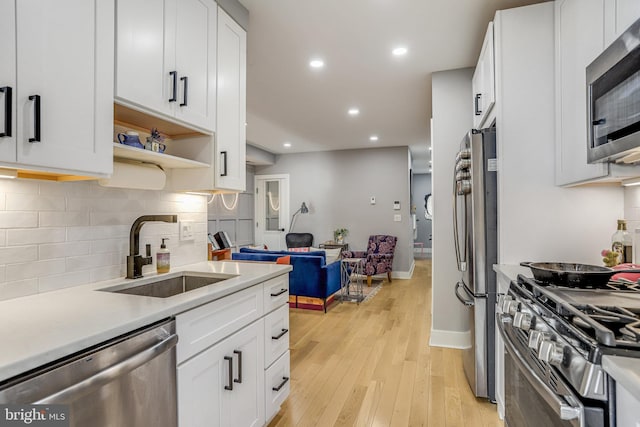 kitchen with appliances with stainless steel finishes, sink, and white cabinets