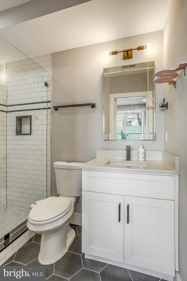 bathroom with vanity, a tile shower, tile patterned floors, and toilet