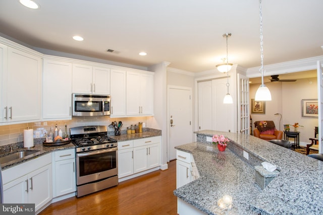 kitchen with pendant lighting, sink, appliances with stainless steel finishes, white cabinetry, and dark hardwood / wood-style floors