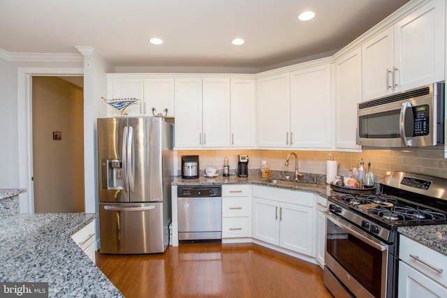 kitchen featuring sink, hardwood / wood-style flooring, stone counters, stainless steel appliances, and white cabinets