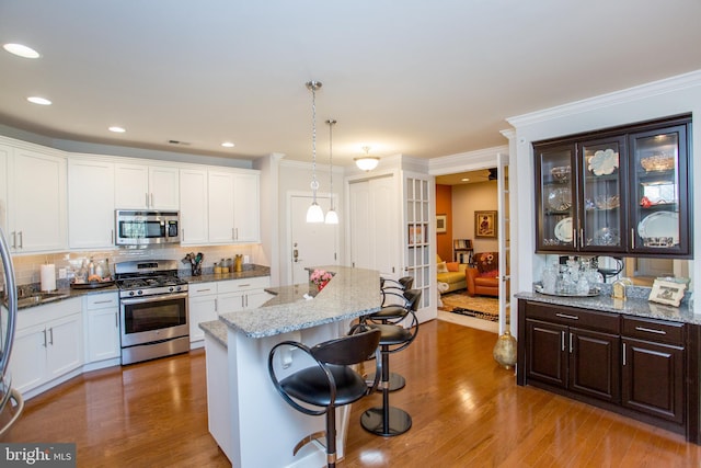 kitchen featuring dark brown cabinetry, decorative light fixtures, a kitchen breakfast bar, a kitchen island, and stainless steel appliances