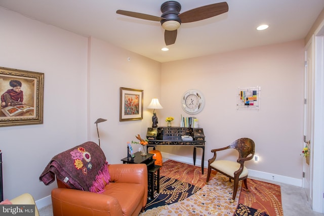 sitting room with ceiling fan and light colored carpet