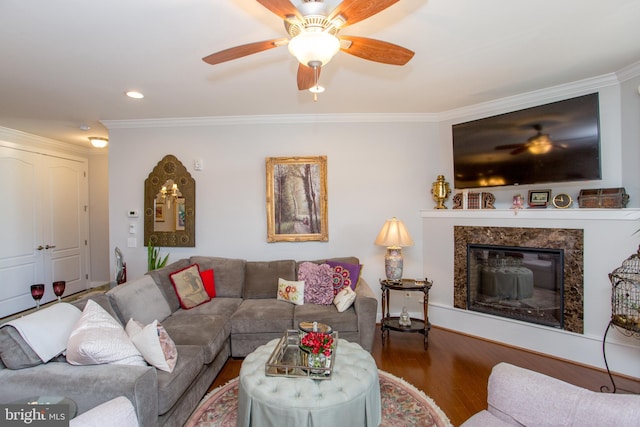 living room with crown molding, ceiling fan, wood-type flooring, and a fireplace