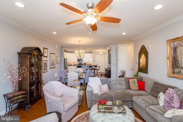 living room featuring ornamental molding, wood-type flooring, and ceiling fan with notable chandelier