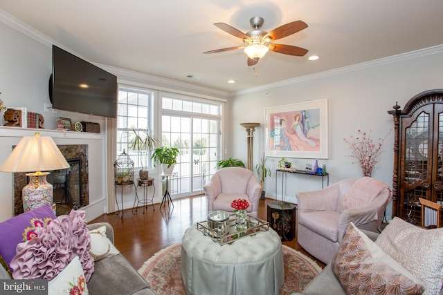 living room featuring ceiling fan, ornamental molding, a premium fireplace, and wood-type flooring