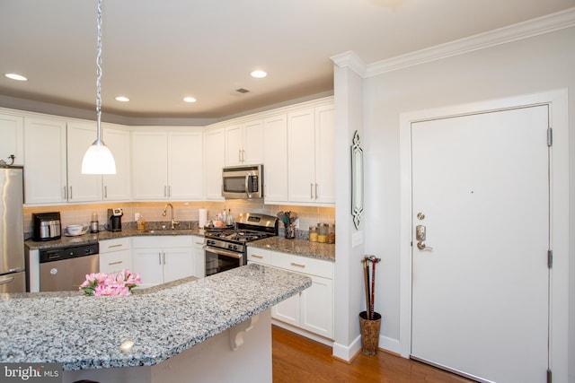 kitchen with sink, white cabinetry, hanging light fixtures, stainless steel appliances, and light stone countertops