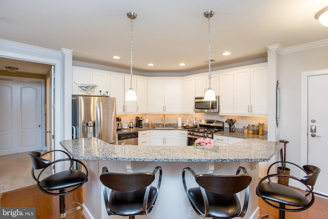 kitchen featuring white cabinetry, hanging light fixtures, light stone countertops, and appliances with stainless steel finishes