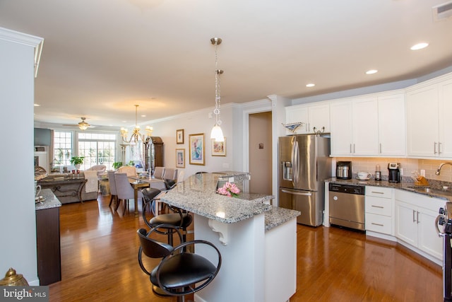 kitchen with sink, a breakfast bar area, appliances with stainless steel finishes, white cabinets, and decorative light fixtures