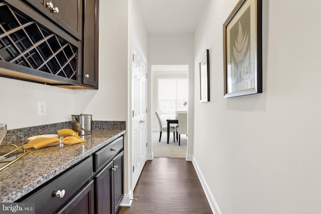 interior space featuring dark brown cabinetry, dark hardwood / wood-style flooring, and dark stone counters