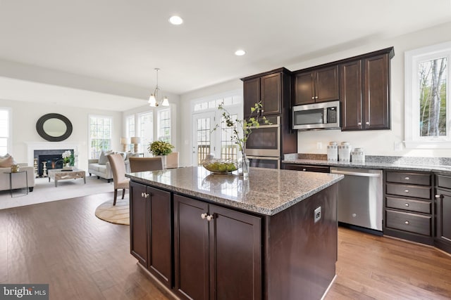 kitchen featuring a kitchen island, appliances with stainless steel finishes, dark brown cabinets, and stone counters