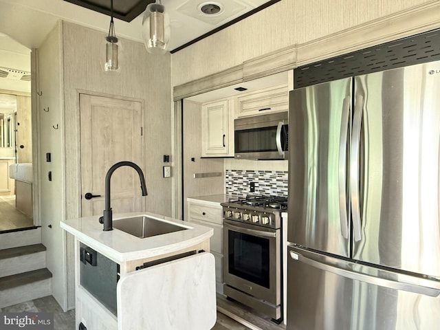 kitchen with sink, pendant lighting, stainless steel appliances, a kitchen island with sink, and decorative backsplash