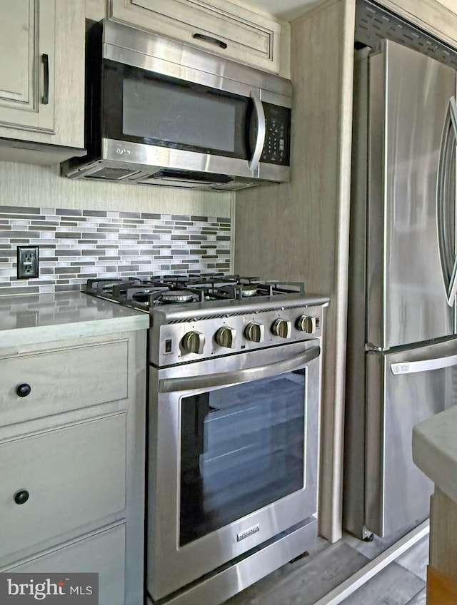 kitchen with cream cabinetry, stainless steel appliances, and backsplash