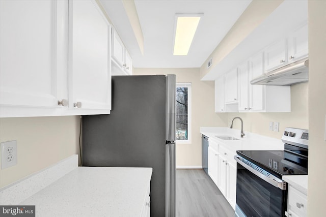 kitchen featuring appliances with stainless steel finishes, sink, white cabinets, and light hardwood / wood-style flooring