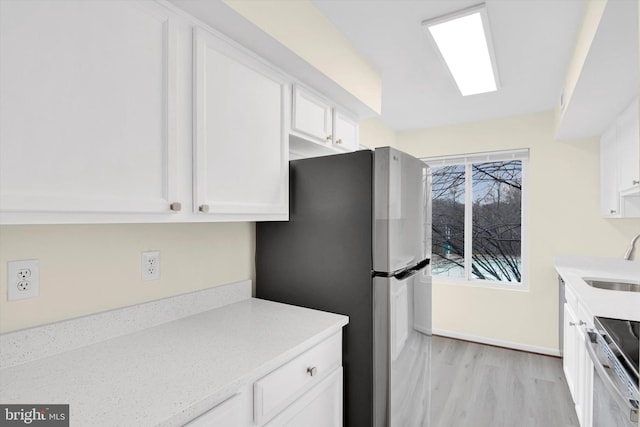 kitchen featuring stainless steel appliances, sink, light hardwood / wood-style flooring, and white cabinets