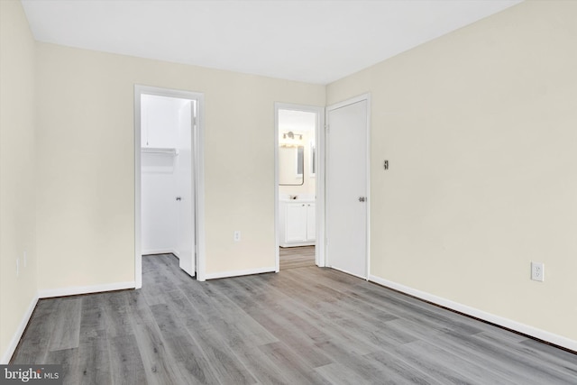 unfurnished bedroom with a spacious closet, light wood-type flooring, and a closet