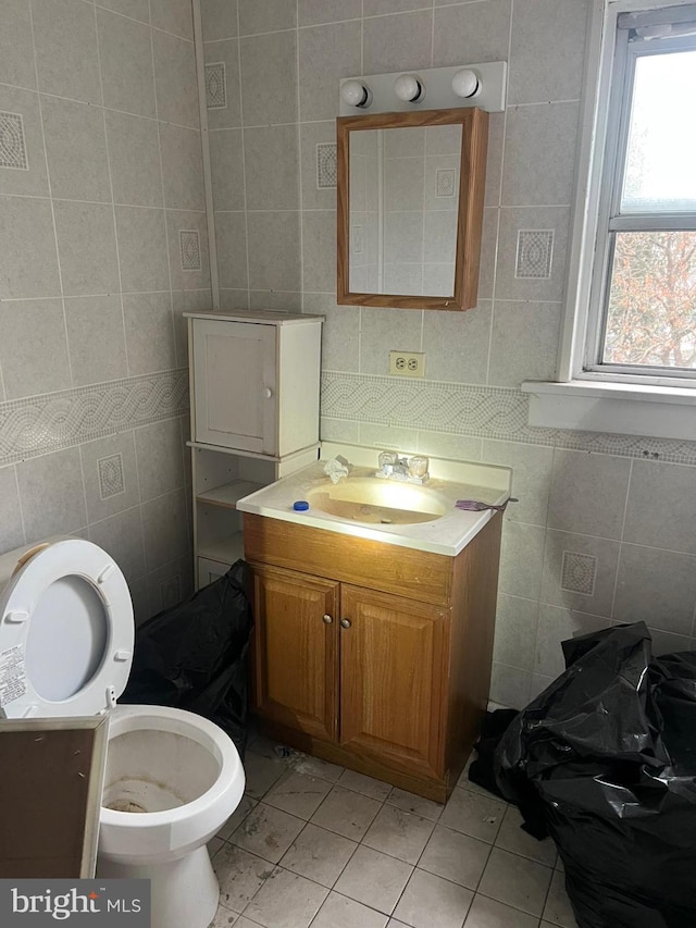 bathroom with vanity, toilet, and tile walls