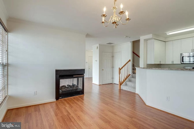 unfurnished living room featuring crown molding, a multi sided fireplace, a chandelier, and light hardwood / wood-style floors