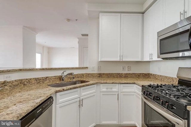 kitchen featuring appliances with stainless steel finishes, sink, white cabinets, and light stone counters