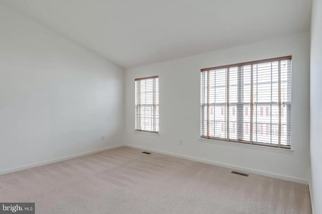 carpeted empty room featuring lofted ceiling