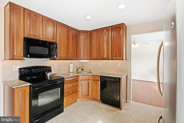 kitchen with tasteful backsplash, light stone countertops, sink, and black appliances