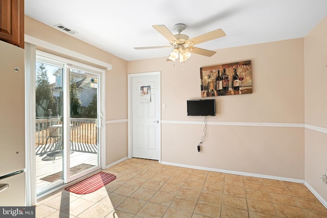 doorway with ceiling fan and light tile patterned floors