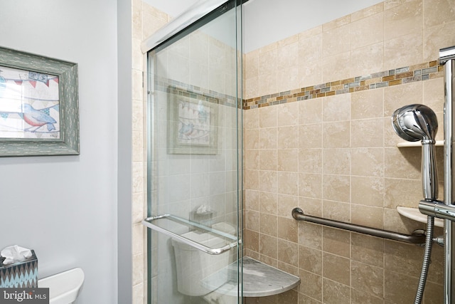 bathroom featuring a shower with door and toilet