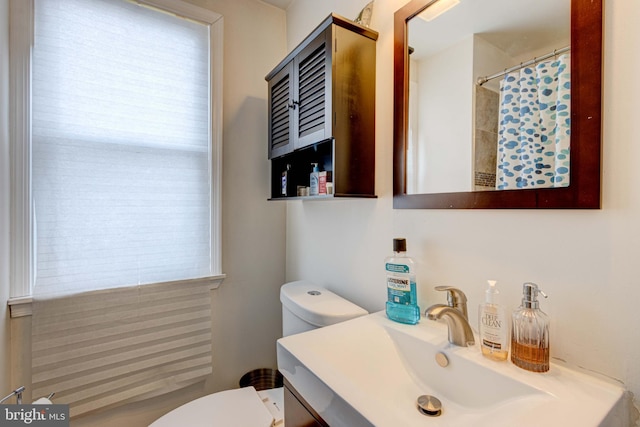 bathroom featuring vanity, a healthy amount of sunlight, and toilet