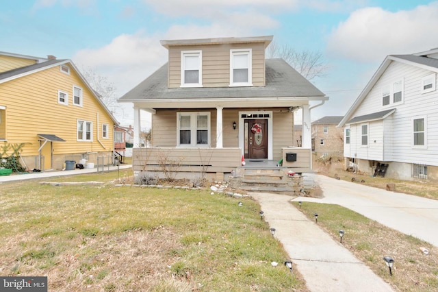 bungalow featuring covered porch and a front yard