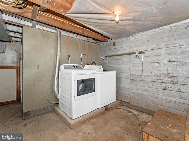 washroom with washing machine and clothes dryer and wood walls