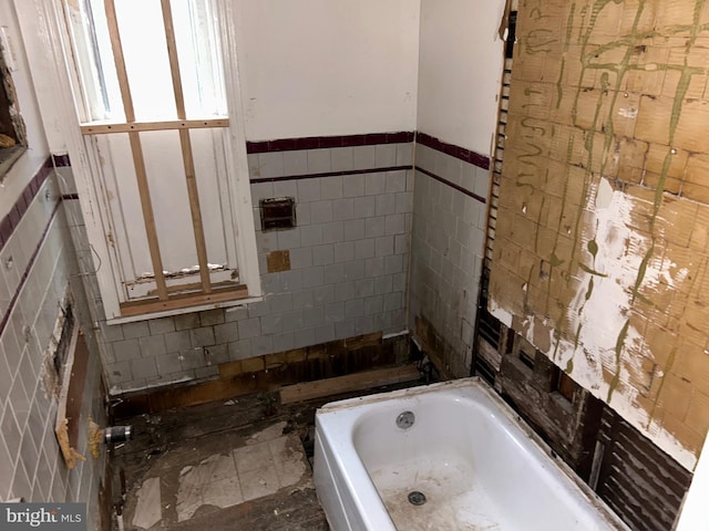 bathroom featuring tile walls and a tub to relax in