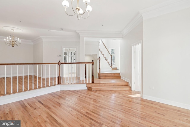 spare room featuring ornamental molding, a chandelier, and light wood-type flooring