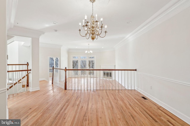 spare room featuring ornamental molding, a chandelier, and light wood-type flooring