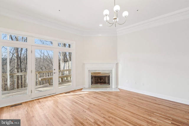 unfurnished living room with crown molding, a high end fireplace, light hardwood / wood-style floors, and a notable chandelier