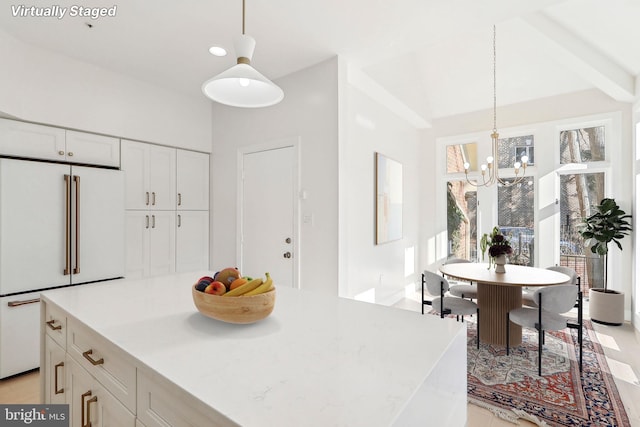 kitchen featuring white cabinets, hanging light fixtures, a center island, light stone countertops, and high end fridge