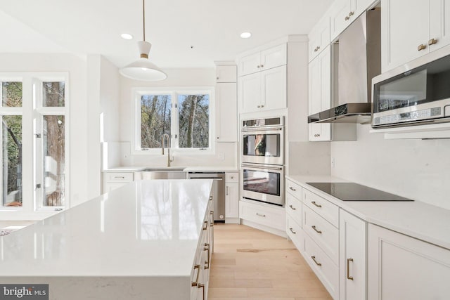 kitchen with sink, appliances with stainless steel finishes, white cabinetry, extractor fan, and decorative light fixtures