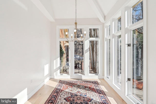 sunroom / solarium with vaulted ceiling with beams, plenty of natural light, and a chandelier