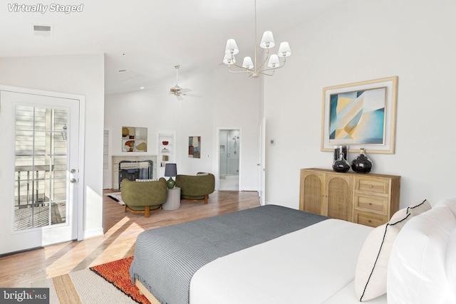 bedroom featuring access to exterior, hardwood / wood-style floors, a notable chandelier, and high vaulted ceiling