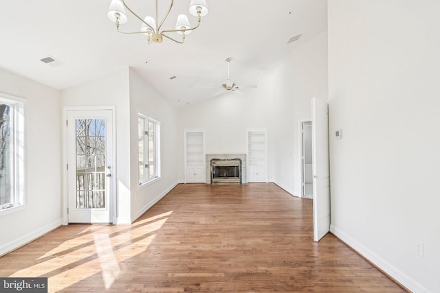 unfurnished living room with vaulted ceiling, ceiling fan with notable chandelier, and hardwood / wood-style floors