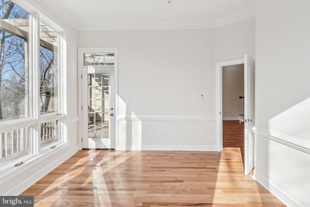 empty room with ornamental molding and light wood-type flooring