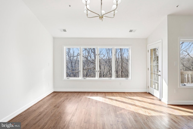 unfurnished dining area with a chandelier and light wood-type flooring