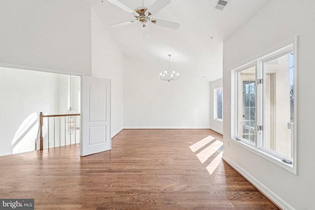 spare room featuring hardwood / wood-style flooring, ceiling fan with notable chandelier, and high vaulted ceiling