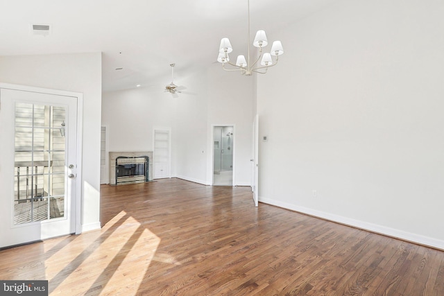 unfurnished living room with hardwood / wood-style flooring, ceiling fan with notable chandelier, and high vaulted ceiling